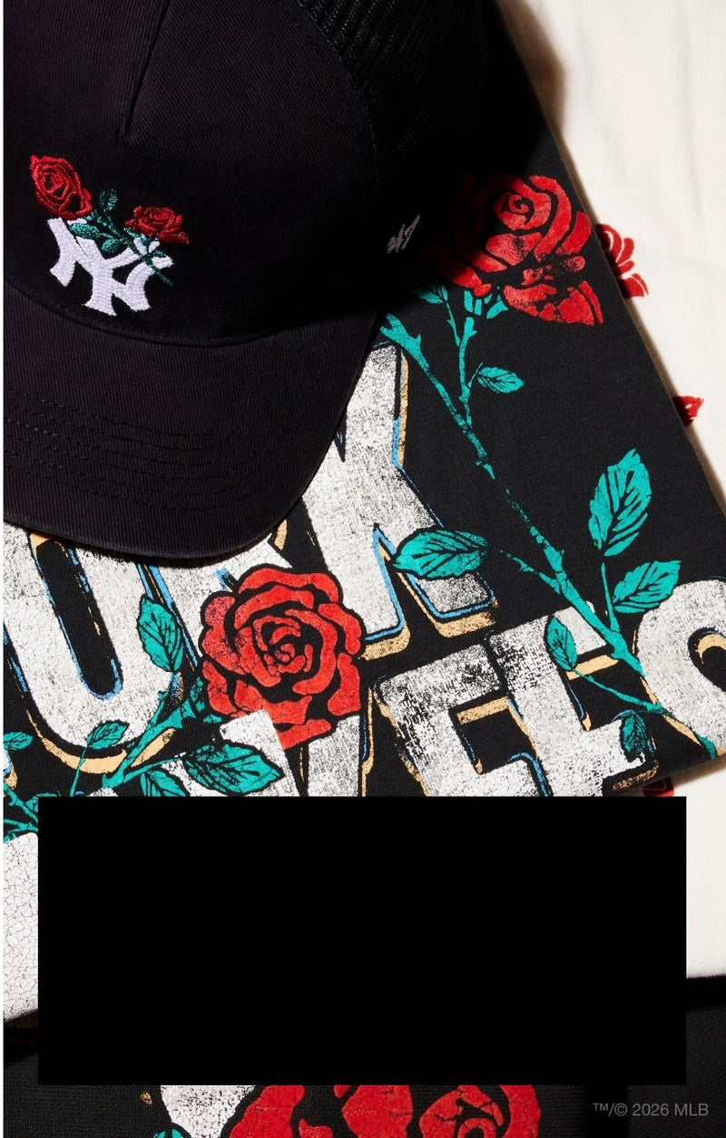 A black baseball cap with embroidered red roses and a white NY logo, layered over a black graphic T-shirt featuring distressed white letters, red roses, and teal leaves.